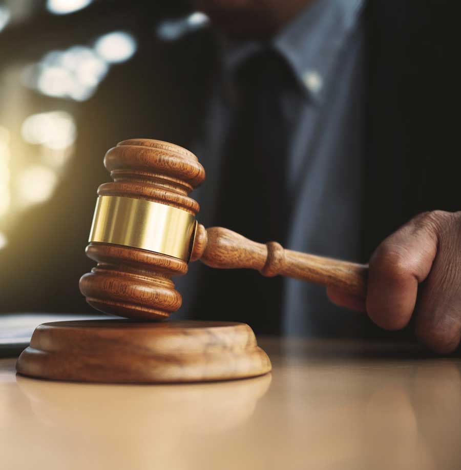 A man in a dark suit striking a judge's gavel on a sound block